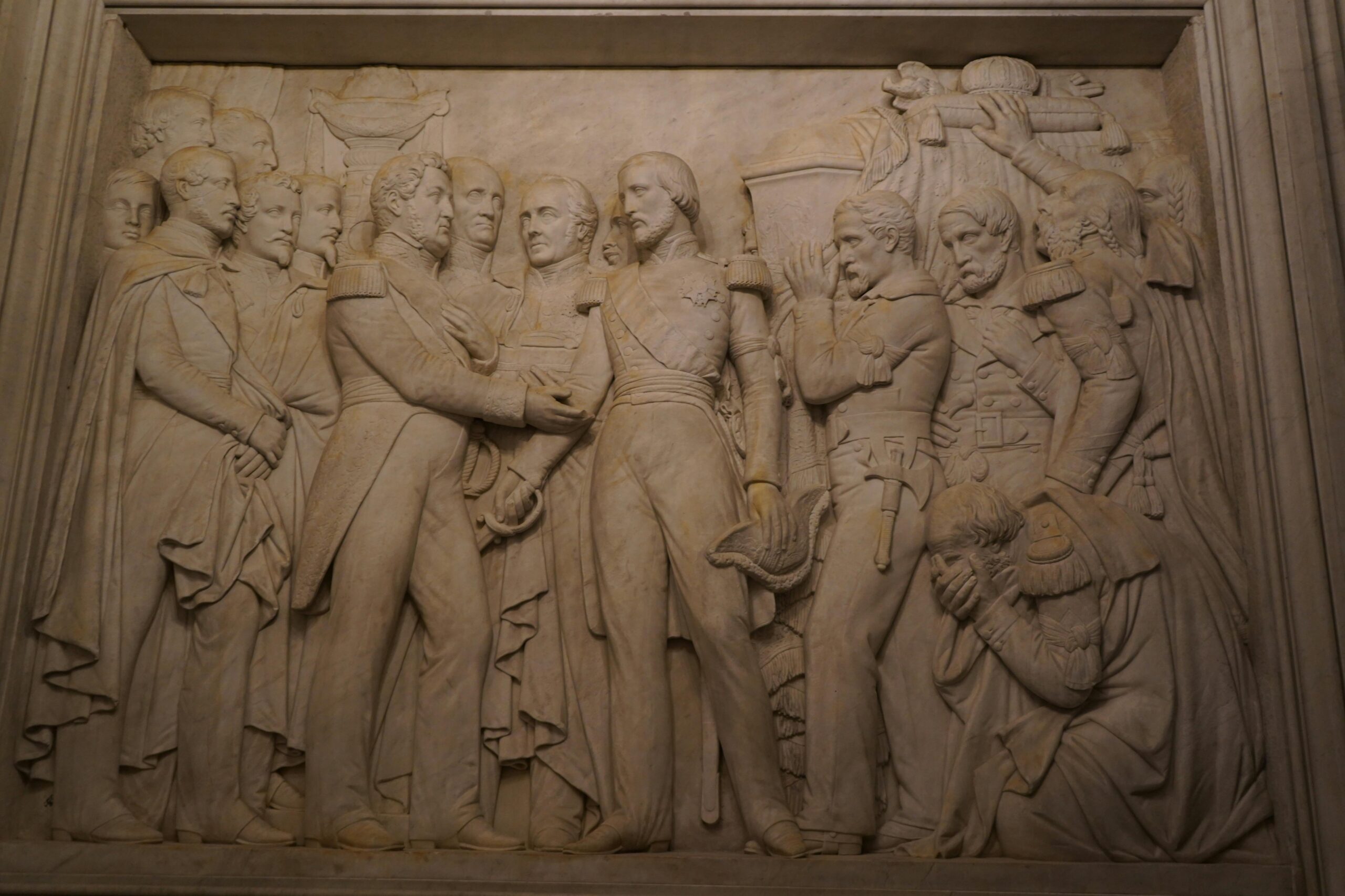 Detailed bas relief sculpture depicting historical figures, captured indoors in Paris.